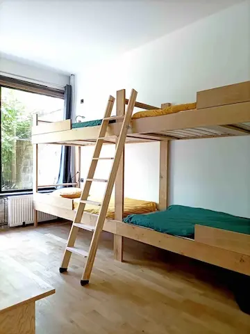 Chambre enfant avec deux lits superposés et une grande baie vitrée sur le jardin.