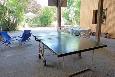 Espace extérieur couvert avec table pour manger et table de ping pong.