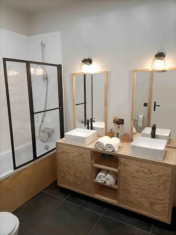Salle de bain moderne avec double vasque et serviettes fournies.