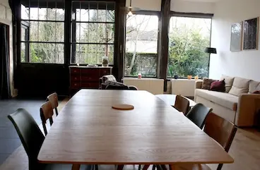 Vue du salon et salle à manger depuis la longue table au milieu de la pièce.